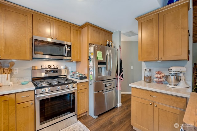 kitchen featuring stainless steel appliances, light stone counters, and dark wood-type flooring