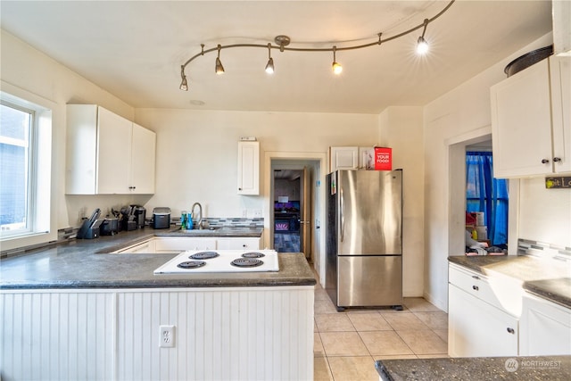 kitchen featuring white cabinetry, light tile patterned floors, white electric cooktop, kitchen peninsula, and stainless steel fridge