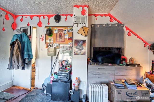 interior space featuring a textured ceiling, radiator, and lofted ceiling