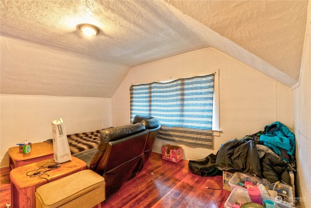 additional living space featuring hardwood / wood-style flooring, a textured ceiling, and lofted ceiling