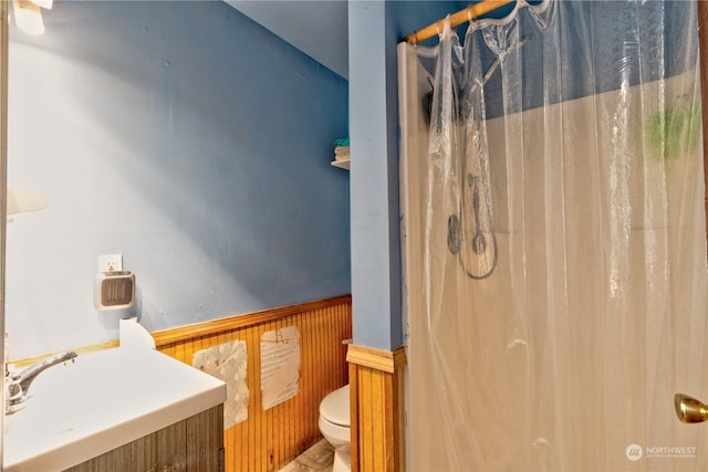 bathroom featuring sink, toilet, wooden walls, and curtained shower