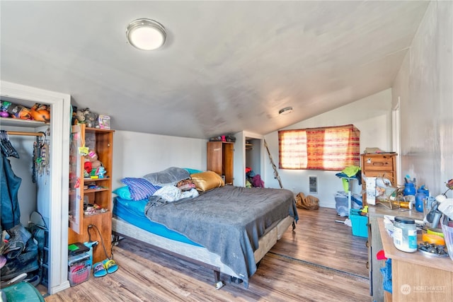 bedroom with hardwood / wood-style flooring, a closet, and vaulted ceiling