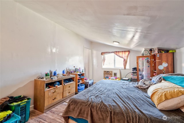 bedroom with vaulted ceiling and light wood-type flooring