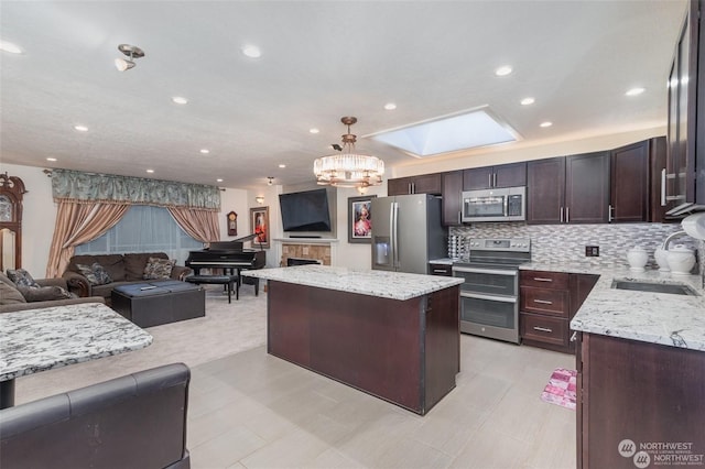 kitchen featuring light stone countertops, a center island, sink, stainless steel appliances, and decorative backsplash