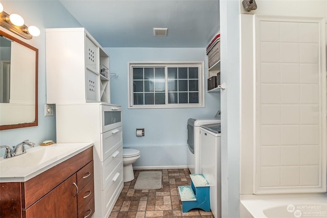 bathroom featuring washer and clothes dryer, vanity, a bath, and toilet