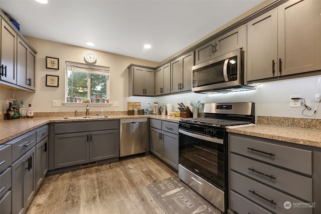 kitchen featuring stainless steel appliances, sink, light hardwood / wood-style floors, and gray cabinetry