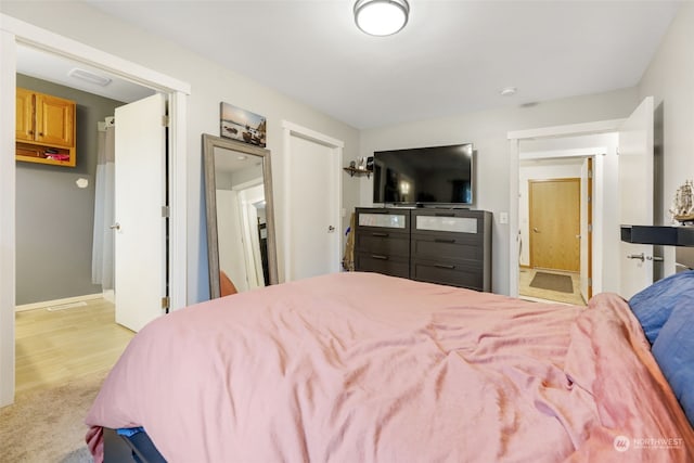 bedroom with light hardwood / wood-style flooring and ensuite bathroom