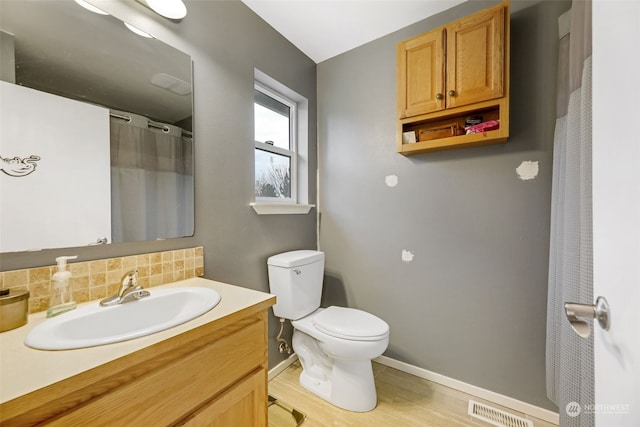 bathroom with toilet, wood-type flooring, tasteful backsplash, and vanity