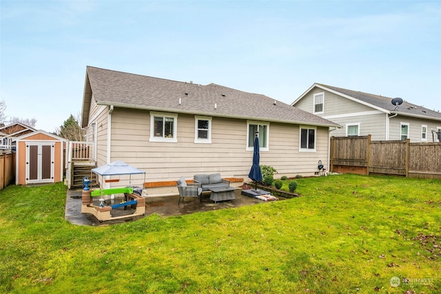 rear view of house featuring a patio, a yard, and a storage shed