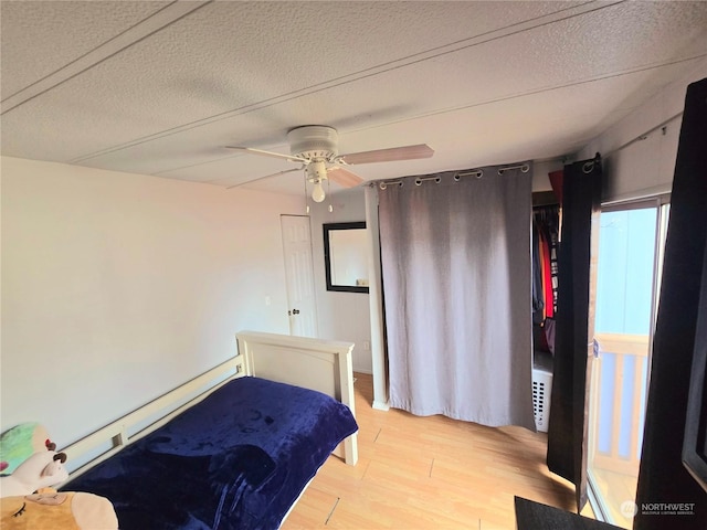 unfurnished bedroom featuring ceiling fan, light hardwood / wood-style floors, a textured ceiling, and a baseboard heating unit