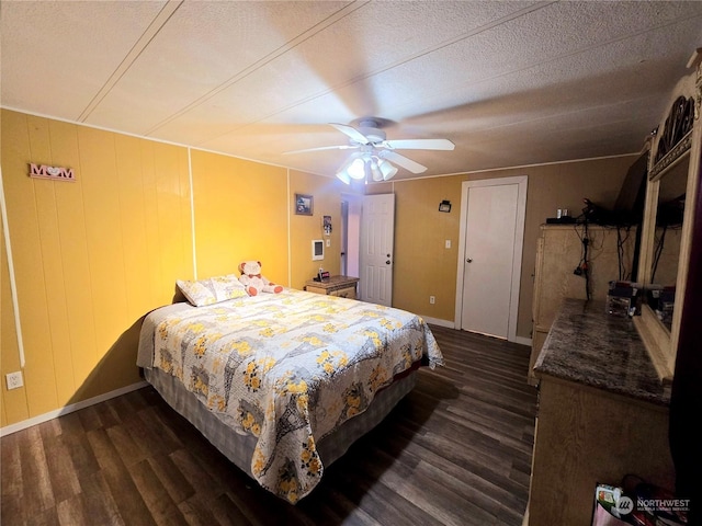 bedroom featuring ceiling fan, wood walls, dark wood-type flooring, and a textured ceiling