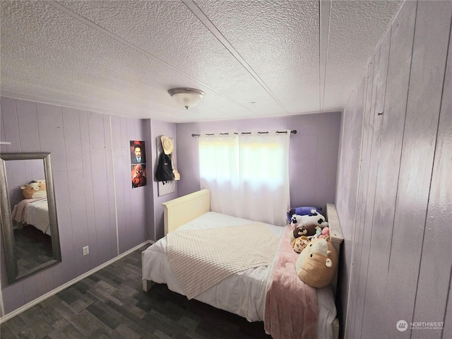 bedroom featuring a textured ceiling, dark wood-type flooring, and wooden walls