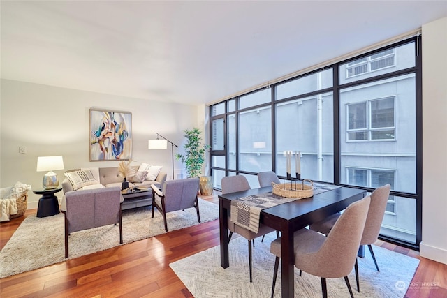 dining area with a wealth of natural light, expansive windows, and hardwood / wood-style flooring