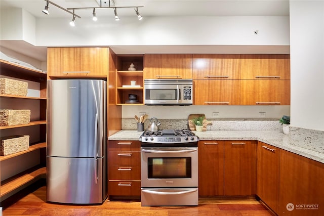 kitchen with light hardwood / wood-style flooring, light stone counters, and appliances with stainless steel finishes