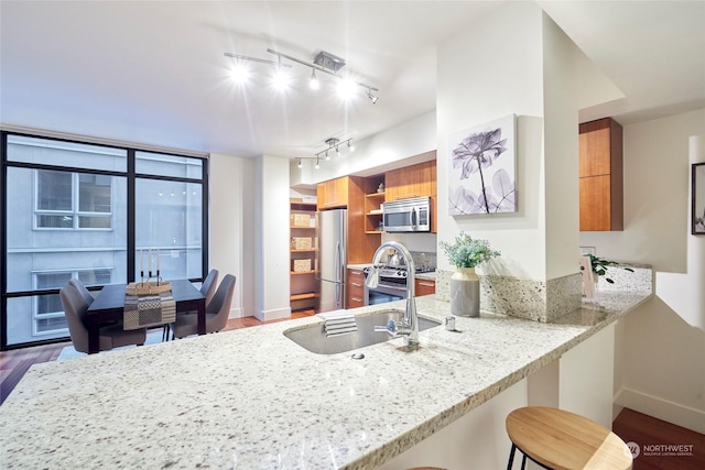 kitchen featuring a breakfast bar area, stainless steel appliances, kitchen peninsula, dark wood-type flooring, and sink