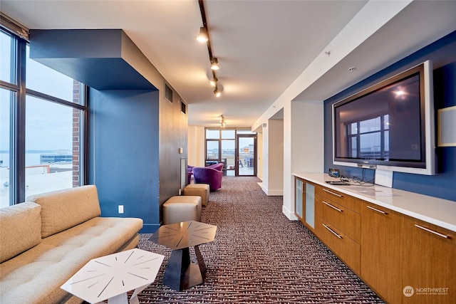 interior space featuring a wall of windows, dark carpet, and a water view