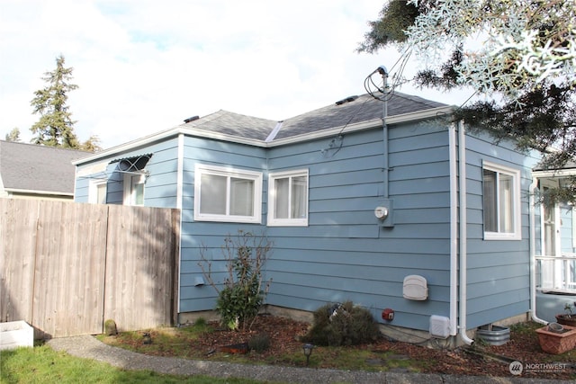 view of property exterior with fence and roof with shingles