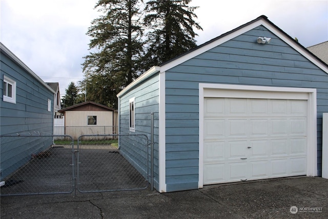 detached garage featuring driveway and fence