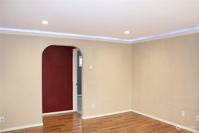 empty room featuring wood-type flooring and ornamental molding