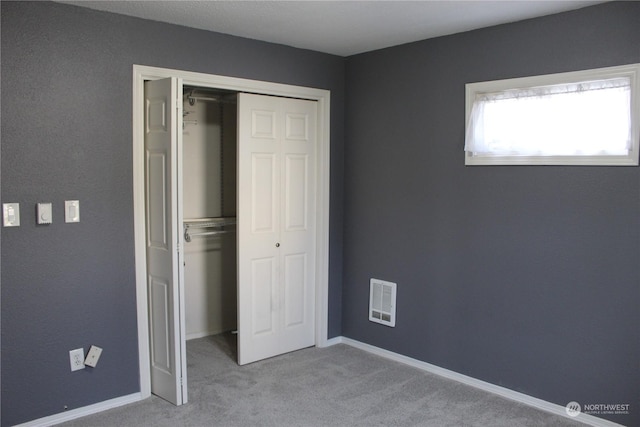 unfurnished bedroom with light carpet and a closet