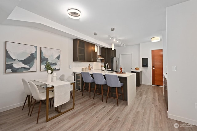 dining space with track lighting, light hardwood / wood-style flooring, and sink