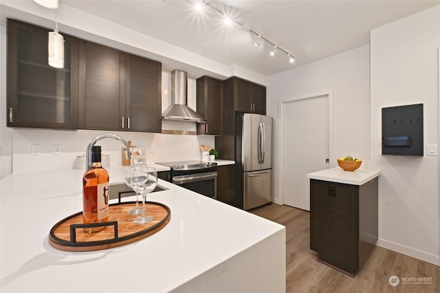 kitchen with dark brown cabinetry, decorative light fixtures, wall chimney range hood, and appliances with stainless steel finishes