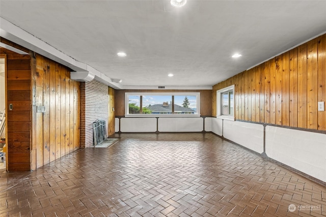 unfurnished room featuring wood walls and a brick fireplace