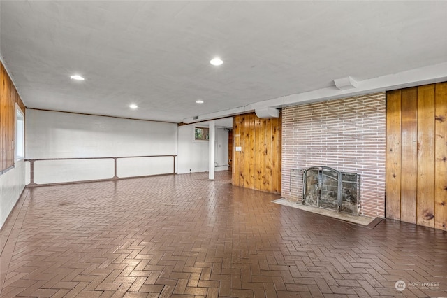 unfurnished living room with a fireplace and wooden walls