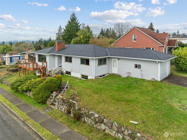 rear view of house with a wooden deck and a yard