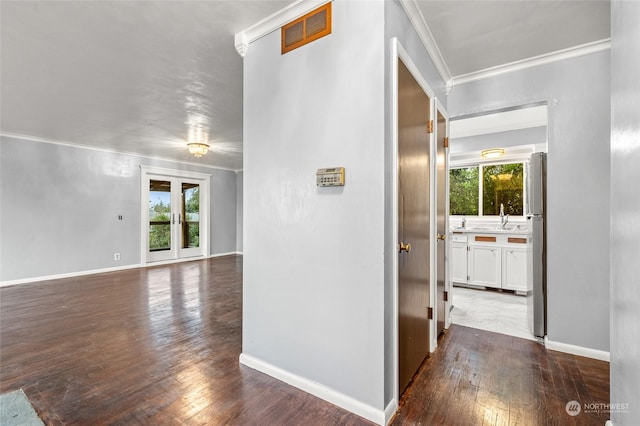 corridor featuring dark wood-type flooring, crown molding, a healthy amount of sunlight, and sink