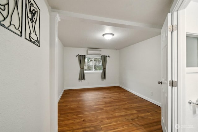 unfurnished room with a textured ceiling, a wall mounted air conditioner, and hardwood / wood-style flooring