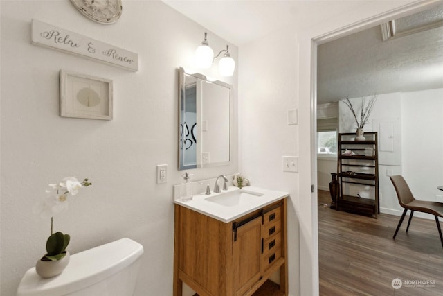 bathroom with toilet, vanity, and hardwood / wood-style flooring