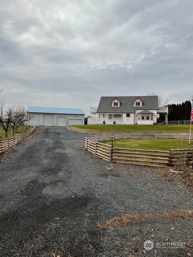 view of front of property featuring a garage, an outbuilding, a front yard, and a rural view