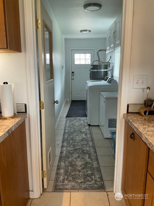 laundry area with independent washer and dryer, electric water heater, and light tile patterned flooring