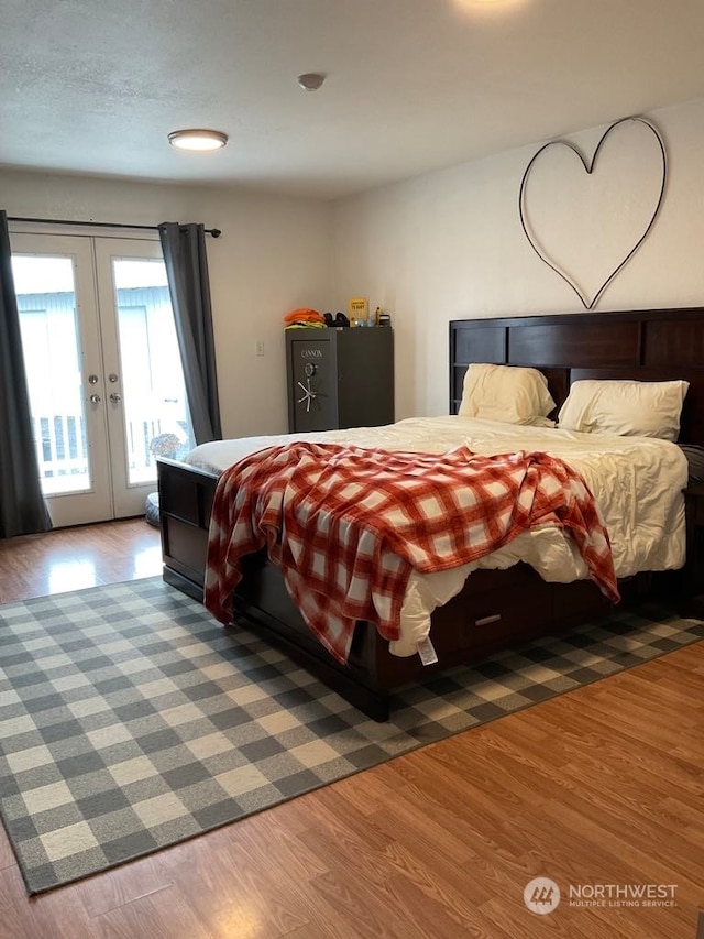 bedroom with hardwood / wood-style floors, access to outside, and french doors