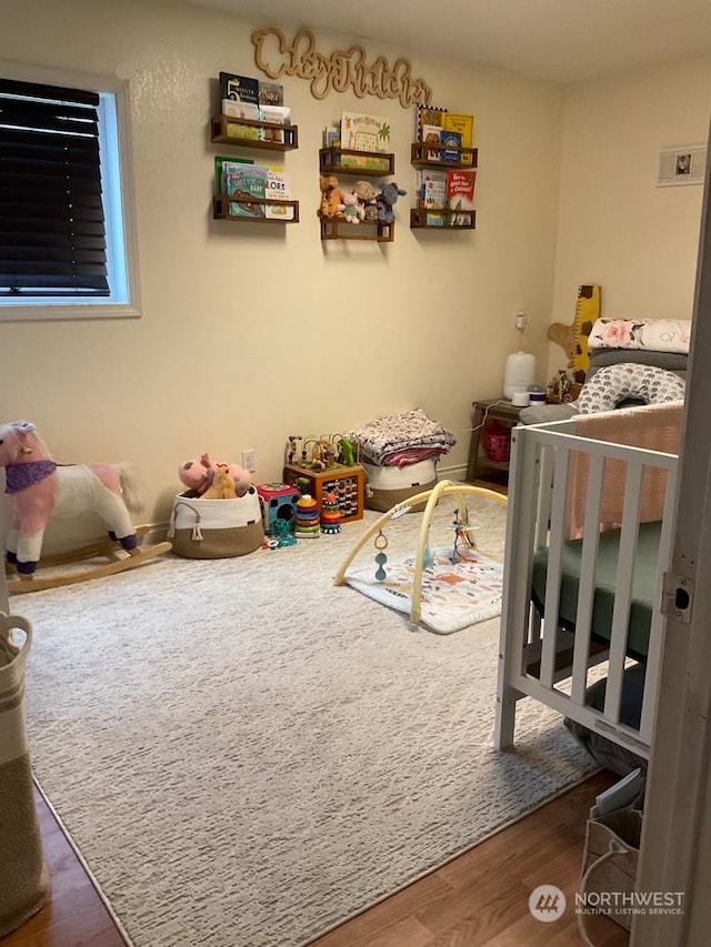 bedroom featuring dark hardwood / wood-style flooring and a nursery area