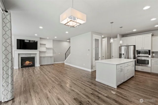 kitchen with stainless steel appliances, decorative light fixtures, white cabinetry, and a center island