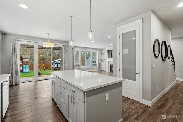 kitchen featuring a kitchen island, light stone countertops, dark hardwood / wood-style floors, and hanging light fixtures