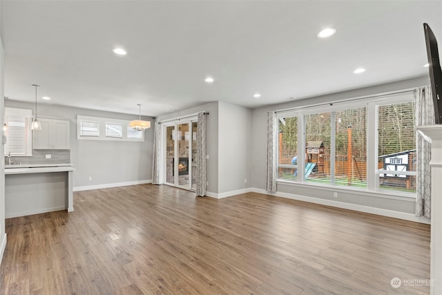 unfurnished living room with sink, light hardwood / wood-style flooring, and a fireplace