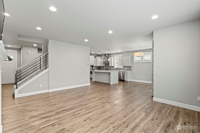 unfurnished living room with sink and light hardwood / wood-style floors