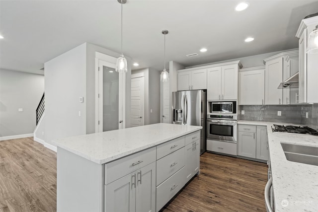 kitchen featuring stainless steel appliances, a center island, dark hardwood / wood-style floors, white cabinets, and backsplash