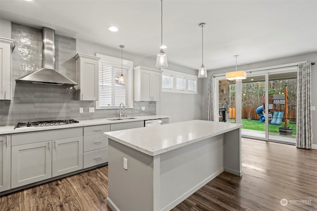 kitchen featuring sink, white cabinets, stainless steel gas cooktop, light stone counters, and wall chimney range hood