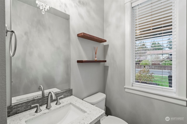 bathroom featuring toilet, vanity, and plenty of natural light