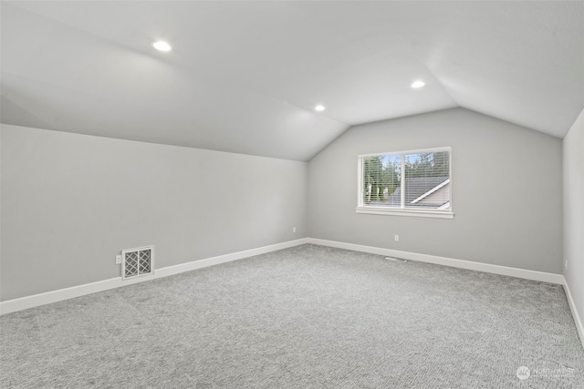 additional living space featuring vaulted ceiling and carpet flooring