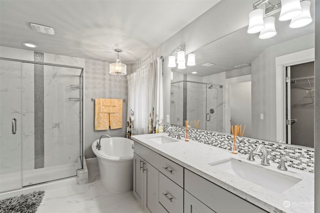 bathroom featuring a notable chandelier, separate shower and tub, backsplash, and vanity