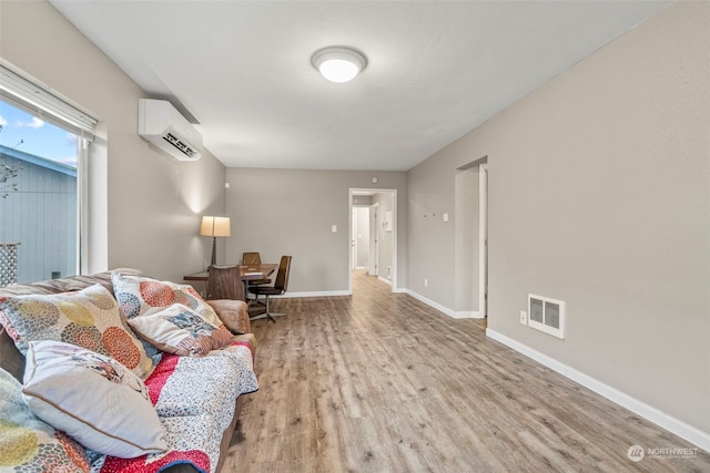 living room with a wall mounted AC and light wood-type flooring