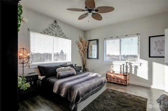 bedroom with ceiling fan with notable chandelier, dark hardwood / wood-style flooring, and multiple windows