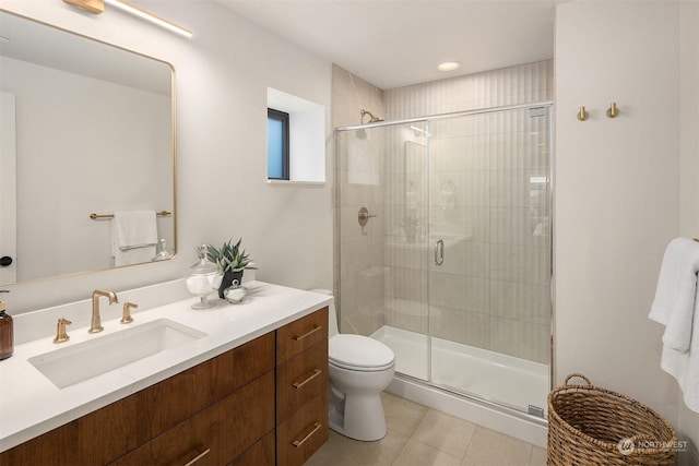 bathroom with tile patterned flooring, vanity, a shower with shower door, and toilet