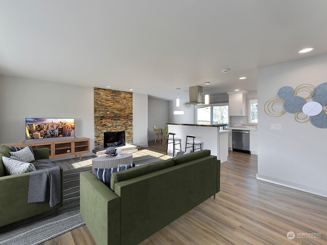 living room with a stone fireplace and light hardwood / wood-style floors