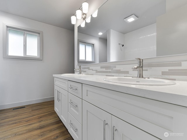 bathroom with hardwood / wood-style flooring, vanity, and decorative backsplash